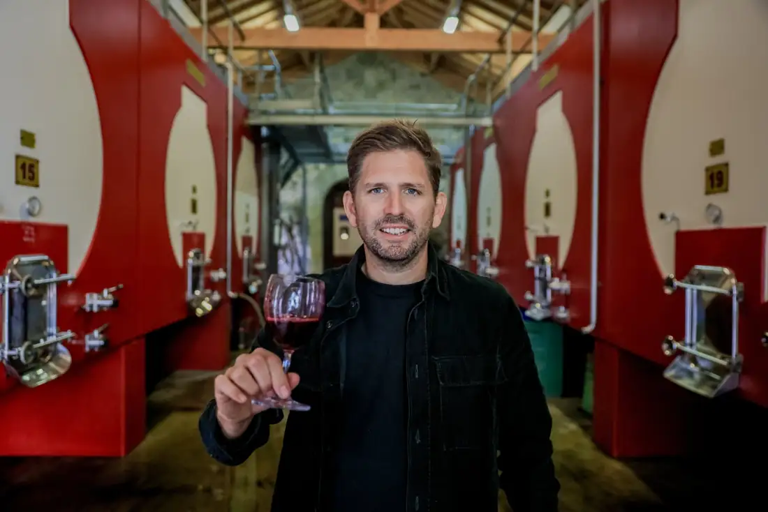 Arthur Yung au cuvier, un verre de vin à la main
